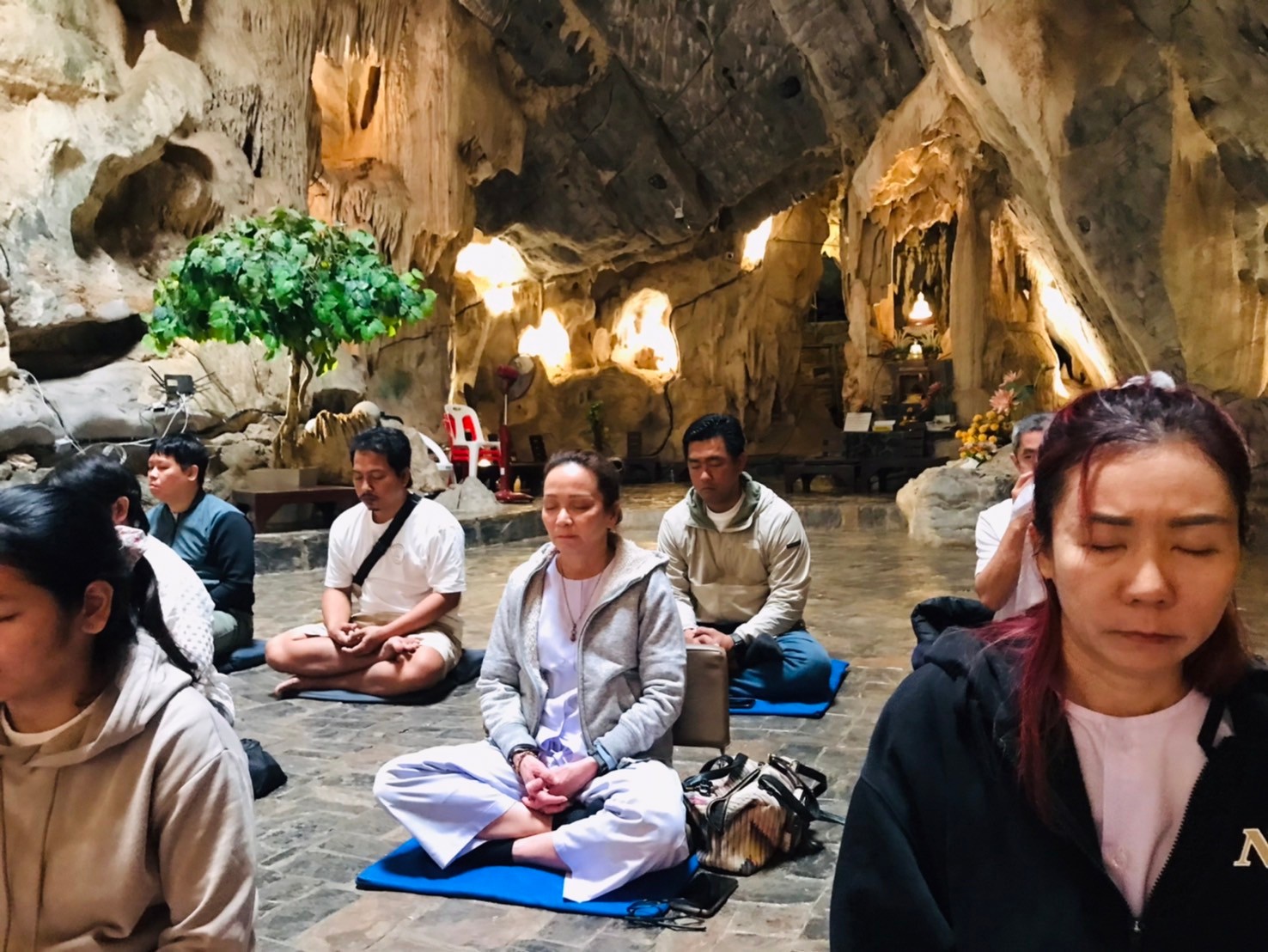 ผู้ปฏิบัติธรรมหลายคนนั่งสมาธิภายในถ้ำที่มีหินงอกหินย้อย